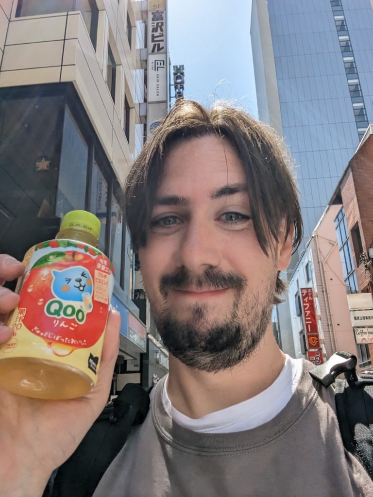 Der Autor hält stolz eine PET-Flasche "Qoo" in der Hand - Ein Apfelsaft-Getränk mit süßer blauer Figur.