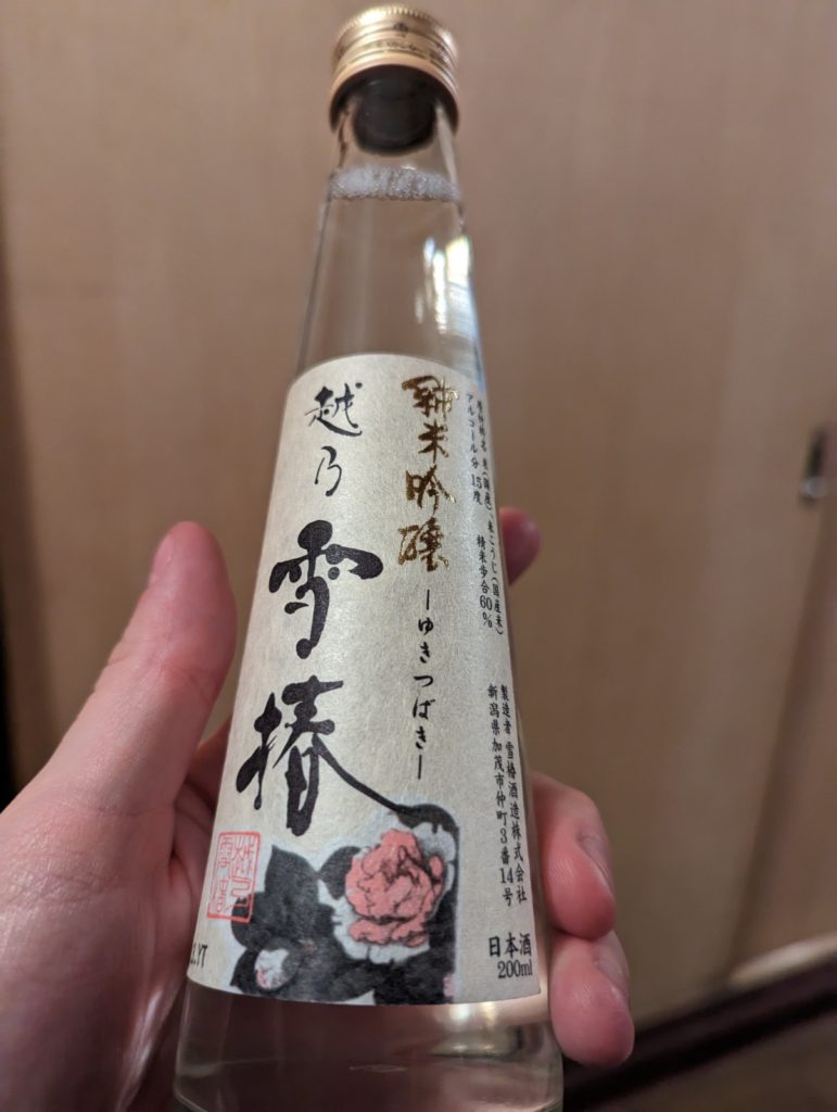 Eine Hand hält eine kleine Sake-Flasche.