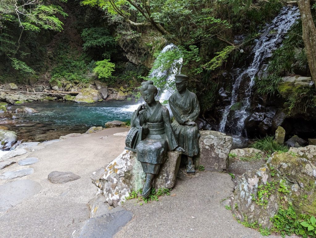 Eine Statue eines sitzenden Päärchens inspiriert vom Roman "Die Tänzerin von Izu" vor dem Wassefall Shokei-Daru.