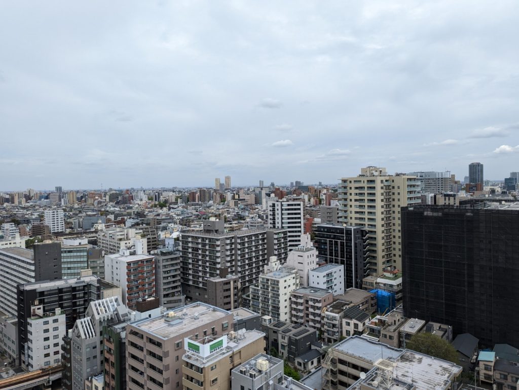 Blick auf Tokyo von einem Riesenrad aus. EIn Meer von Häusern erstreckt sich bis zum Horizont. Es ist bewölkt