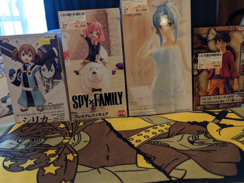 Mehrere Figuren aus diversen Animeserien und ein Handtuch von One Piece.