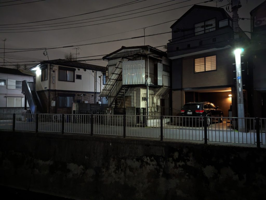 Ein japanisches Wohngebiet in Tokyo Suginami bei Nacht. Vor den Gebäuden ist ein Geländer. bevor es zu einem Fluss runter geht.