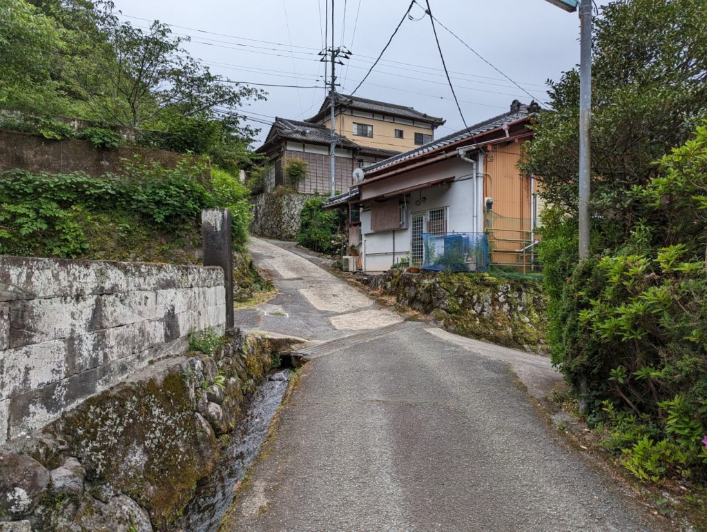 Eine unebene Straße in bergiger Region mit einigen Häusern