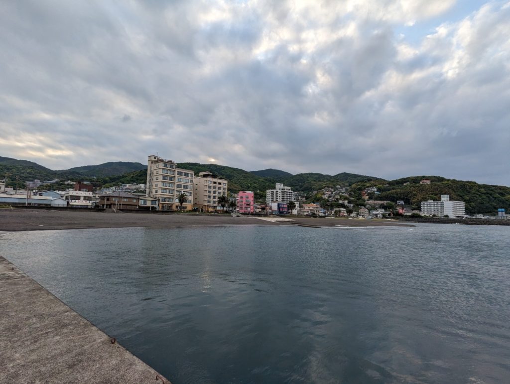 Am Rand einer Küste zeichnen sich Berge bis hin zum Wasser ab. Entlang der Hänge stehen viele kleinere und größere Gebäude.