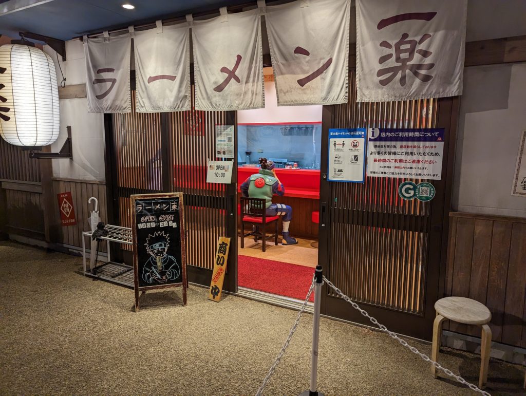 Iruka aus dem Anime Naruto sitzt in einer Ramen-Bar im Fuji Q