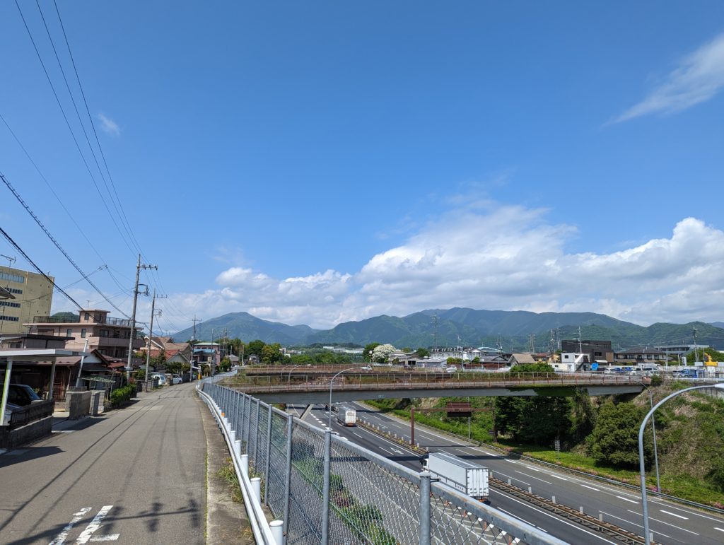 Eine Autobahn in Japan entlang einer Kleinstadt mit Bergen im Hintergrund.