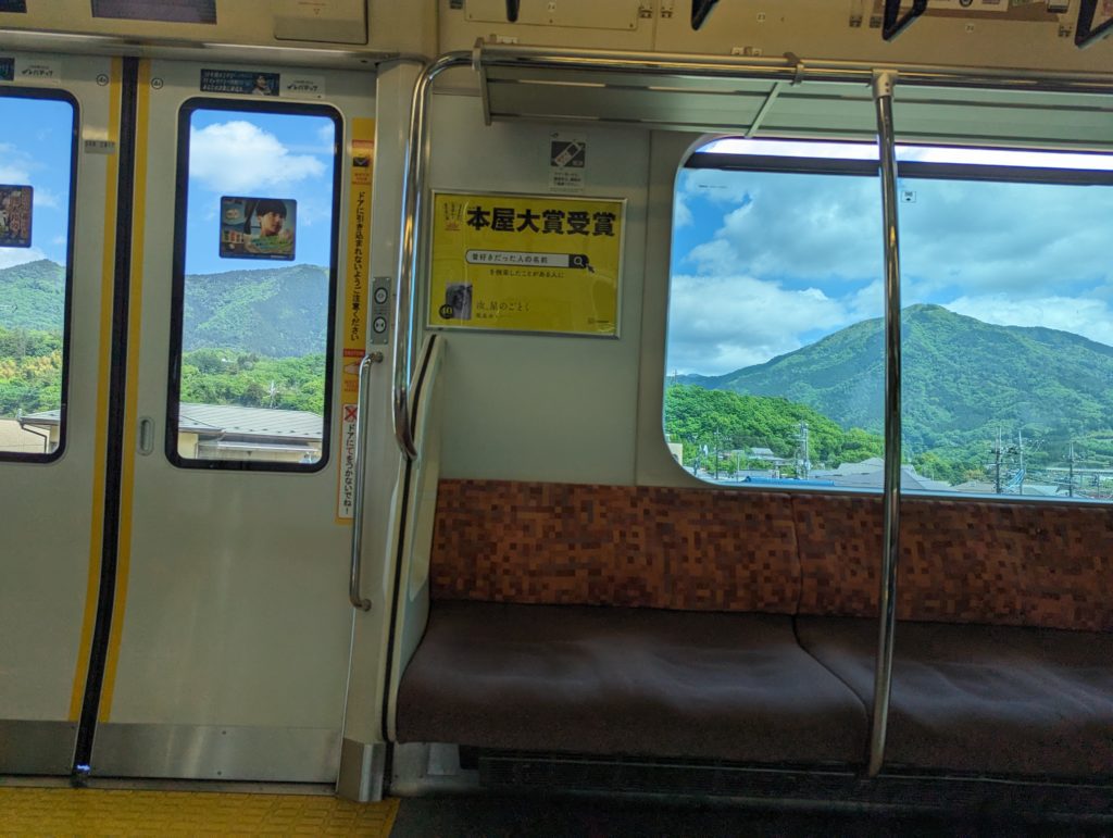 Blick aus den Fenstern einer Bahn, wo man eine bergige Landschaft sieht.