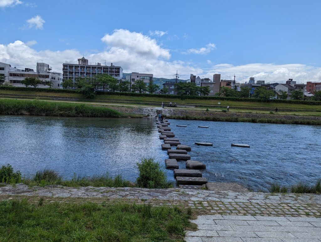 Fluss Kamo in Kyoto mit kleinen Felsen, die einen Weg über den Fluss bieten.