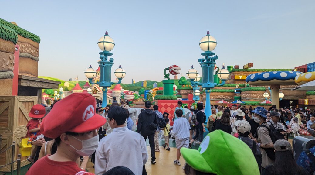 Eine lebendig gewordene Super Nintendo World in den Universal Studios Japan. Einige Gäste tragen Mario-Mützen.