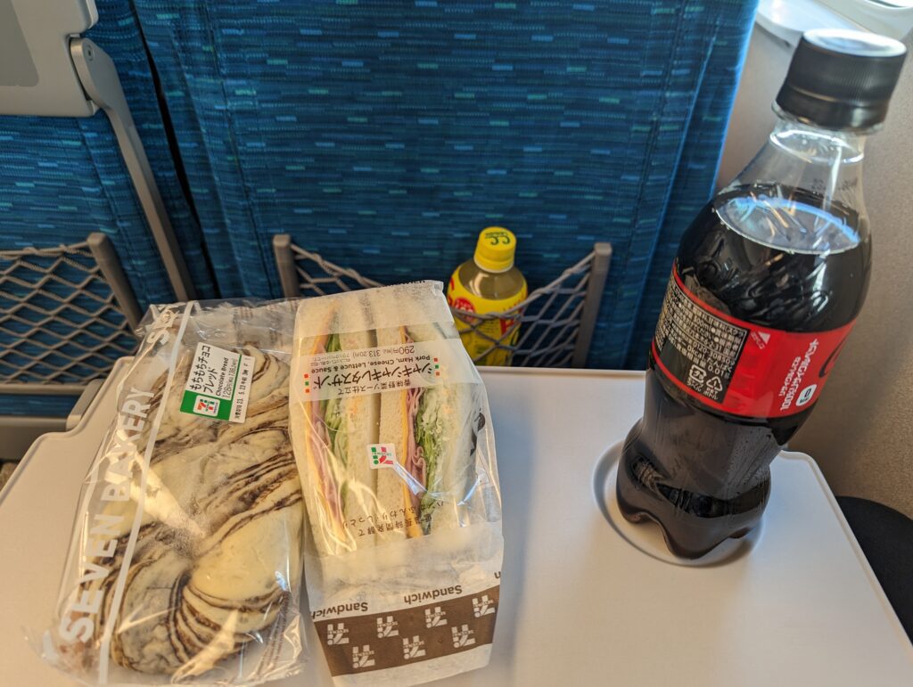 Die Reiseverpflegung im Shinkansen, bestehend aus Schokobrötchen, Cola und Sandwiches aus dem 7/11.