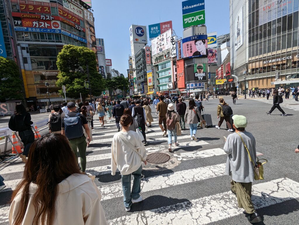 Hunderte Fußgänger überqueren die riesige Kreuzung in Shibuya.